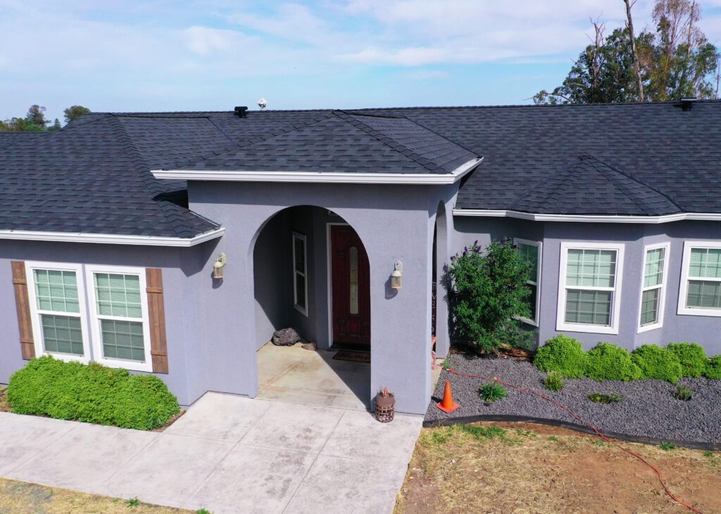 Image of a house with a newly installed dark shingle roof, showcasing the craftsmanship of DavisRoofingGroup in Galt.